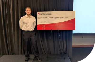 Jackson Ely standing next to the Cardinal 100 check for $10,000